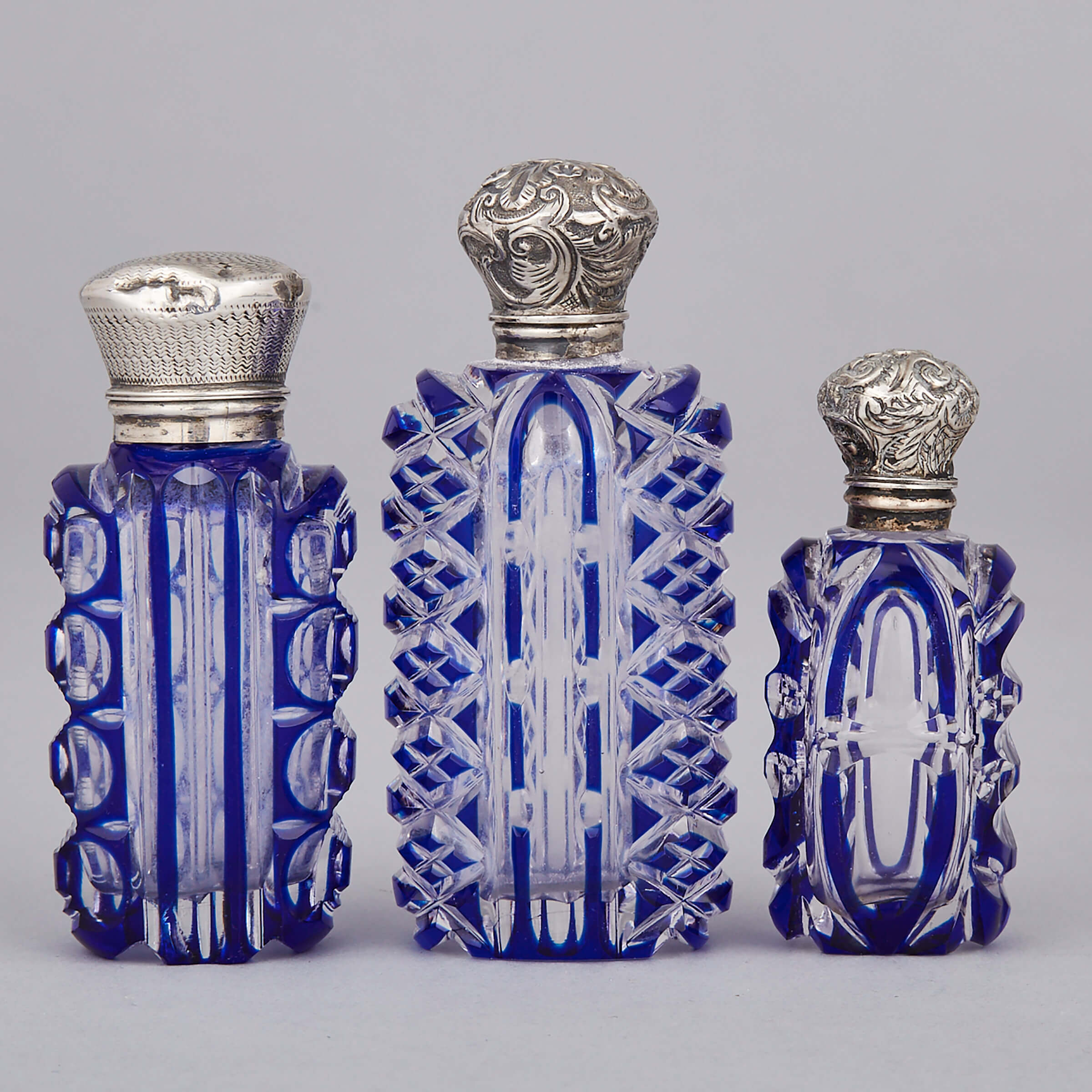 Three Silver Mounted Blue Overlaid and Cut Glass Perfume Bottles, late 19th century